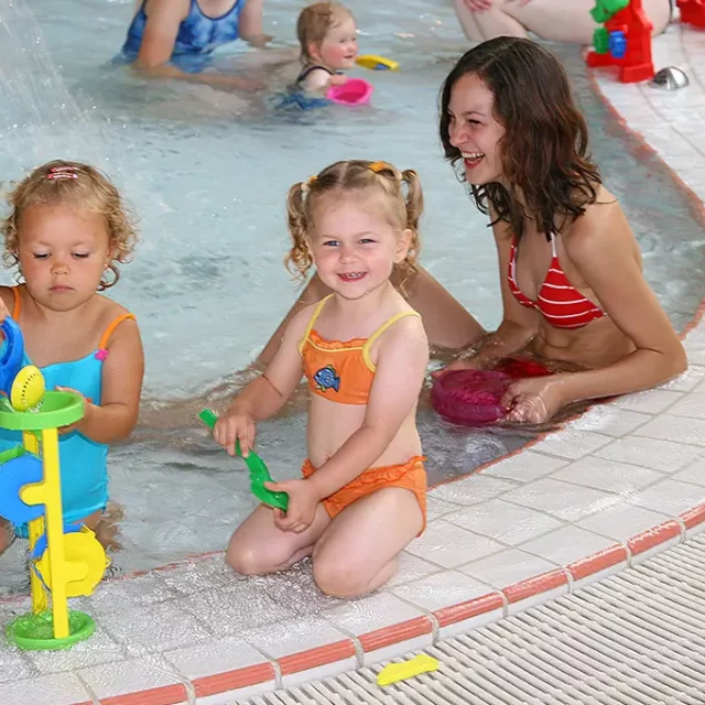 Kinder spielen mit Wasserspielzeug im Kleinkinderbecken