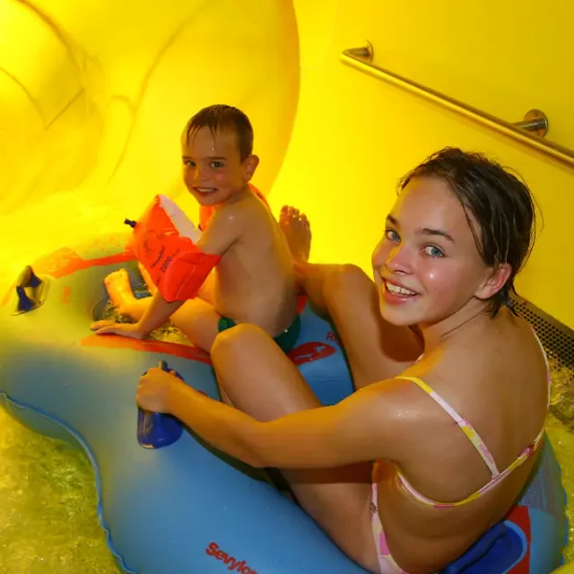 Mädchen und Junge rutschen mit einem Schwimmreifen