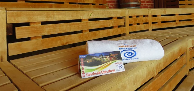 Handtuch und Geschenk-Gutschein auf einer Sitzbank in der Sauna