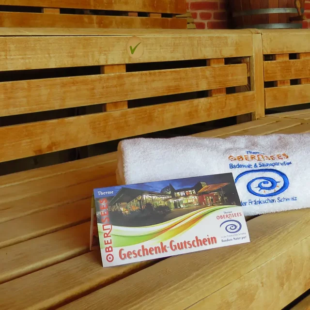 Handtuch und Geschenk-Gutschein auf einer Sitzbank in der Sauna