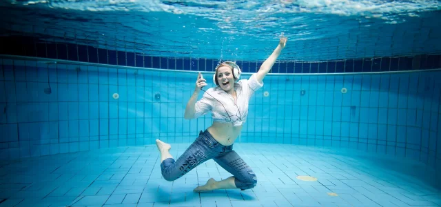 Frau Bekleidet und mit Kopfhörer unter Wasser