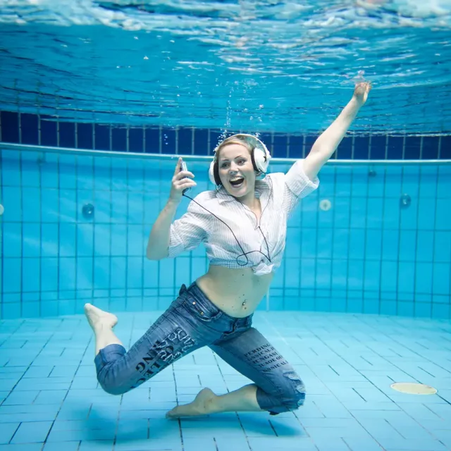 Frau Bekleidet und mit Kopfhörer unter Wasser